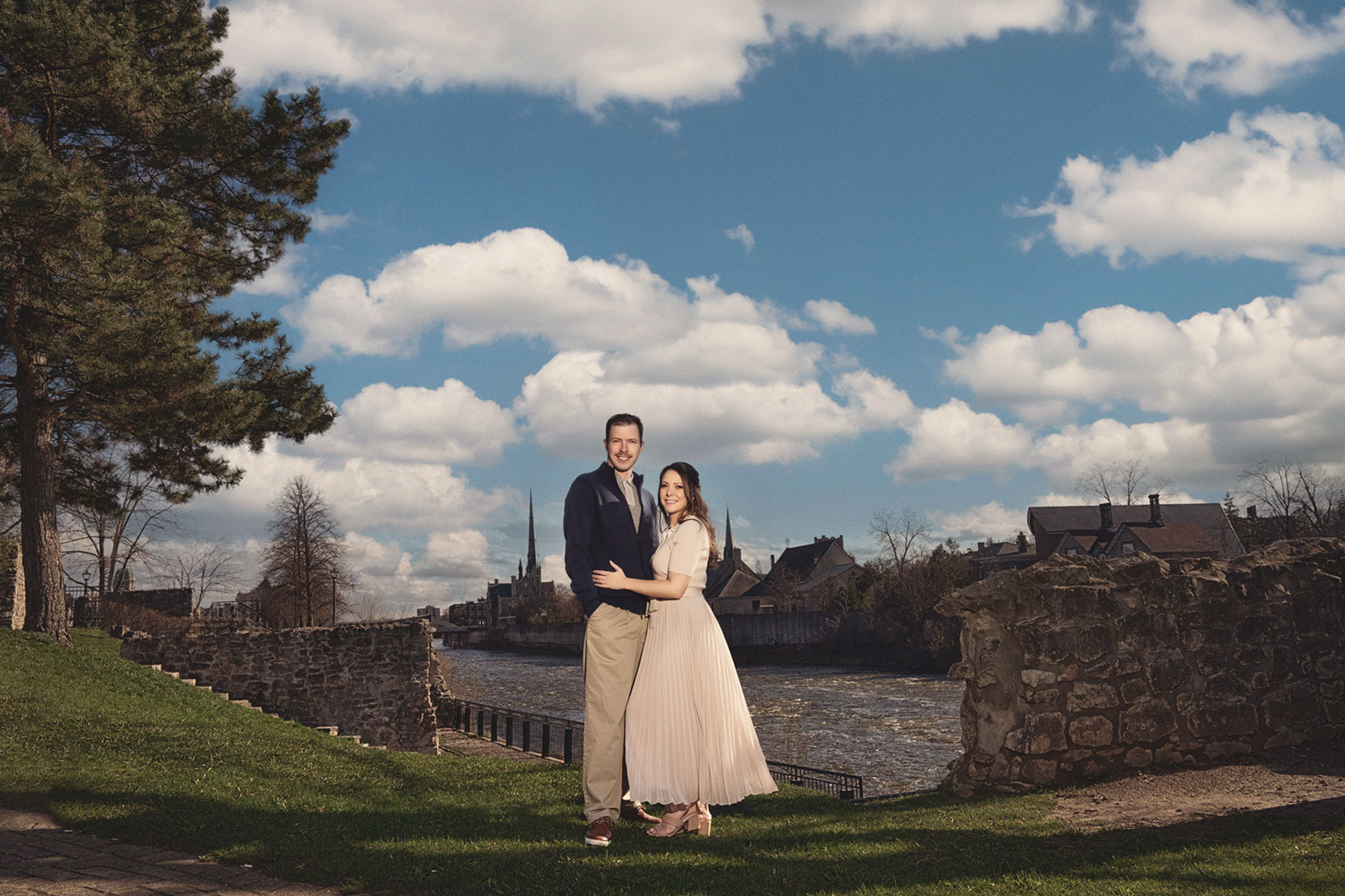 A couple on their engagement shoot, with an urban landscape in the background.