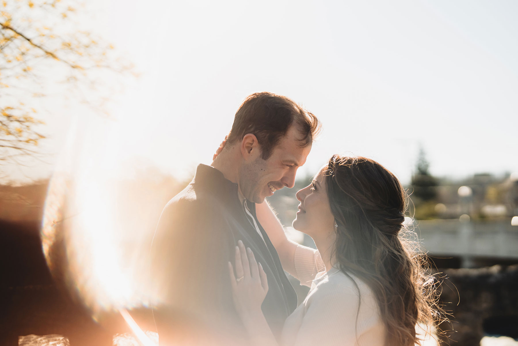 A couple on their engagement shoot, with an urban landscape in the background.