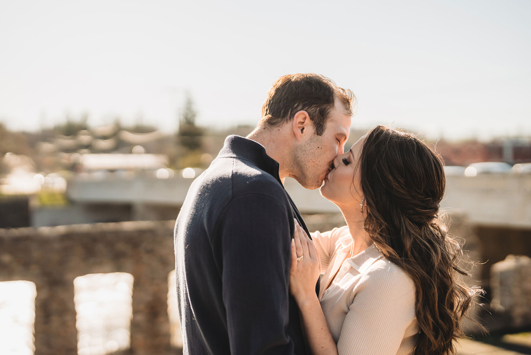 A couple on their engagement shoot, with an urban landscape in the background.