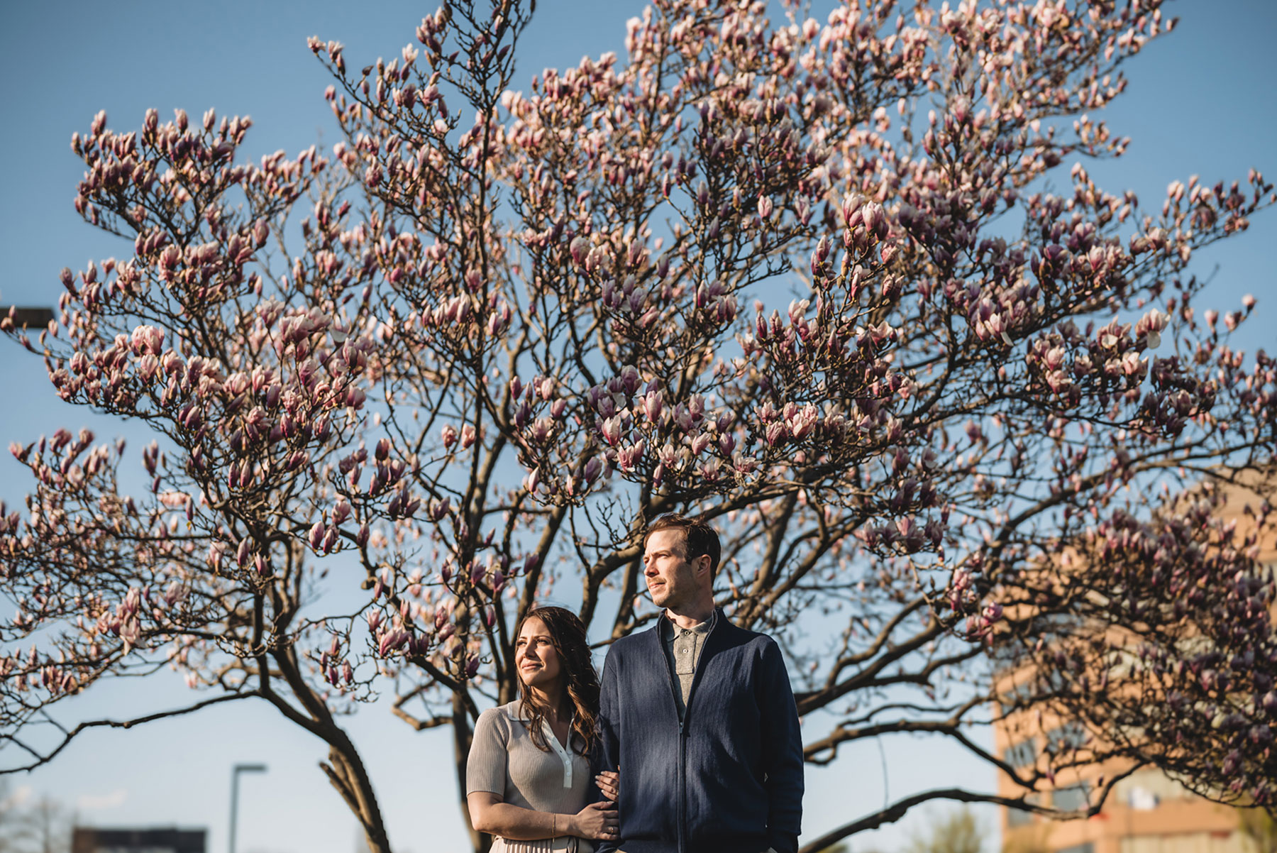 A couple on their engagement shoot, with an urban landscape in the background.