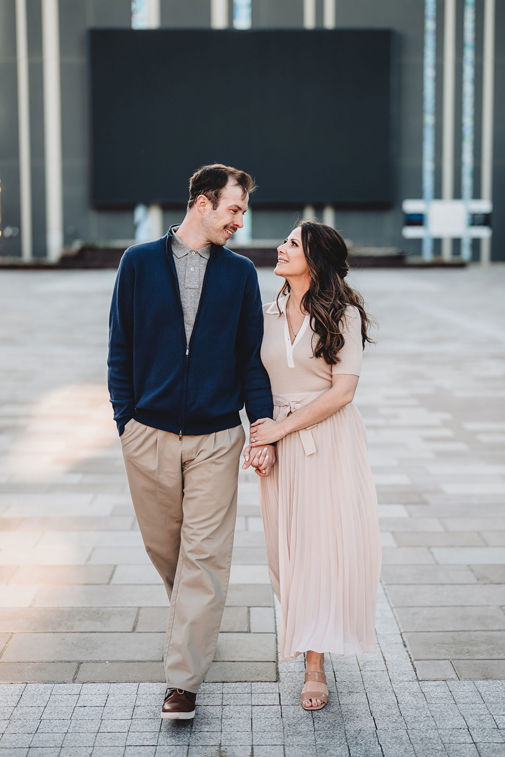 A couple on their engagement shoot, with an urban landscape in the background.