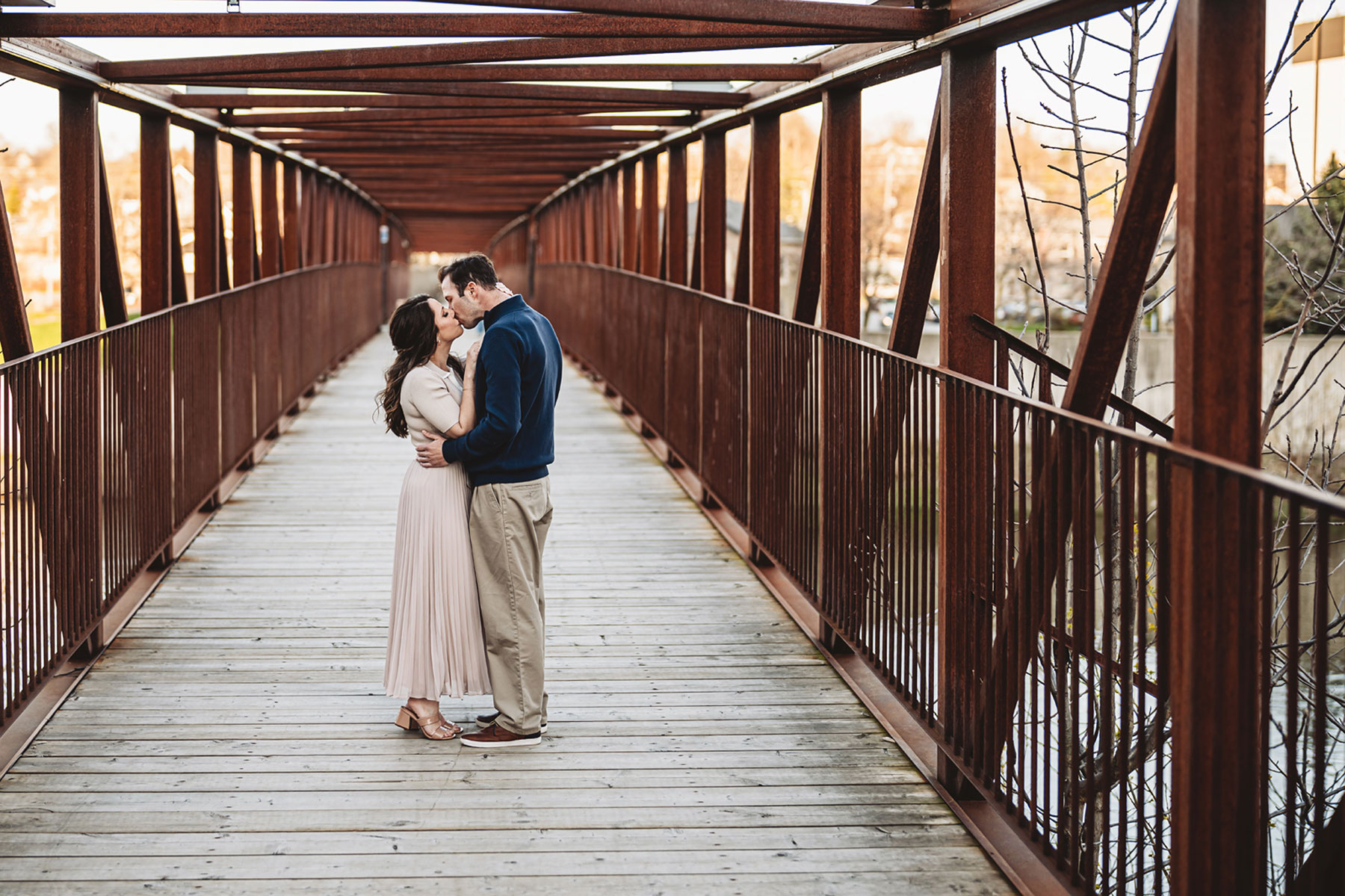 A couple on their engagement shoot, with an urban landscape in the background.