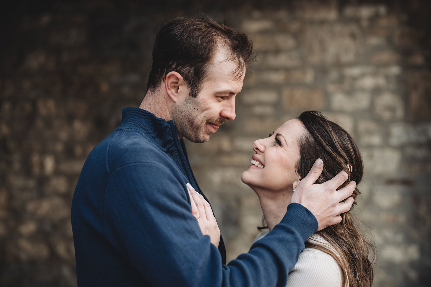 A couple on their engagement shoot, with an urban landscape in the background.