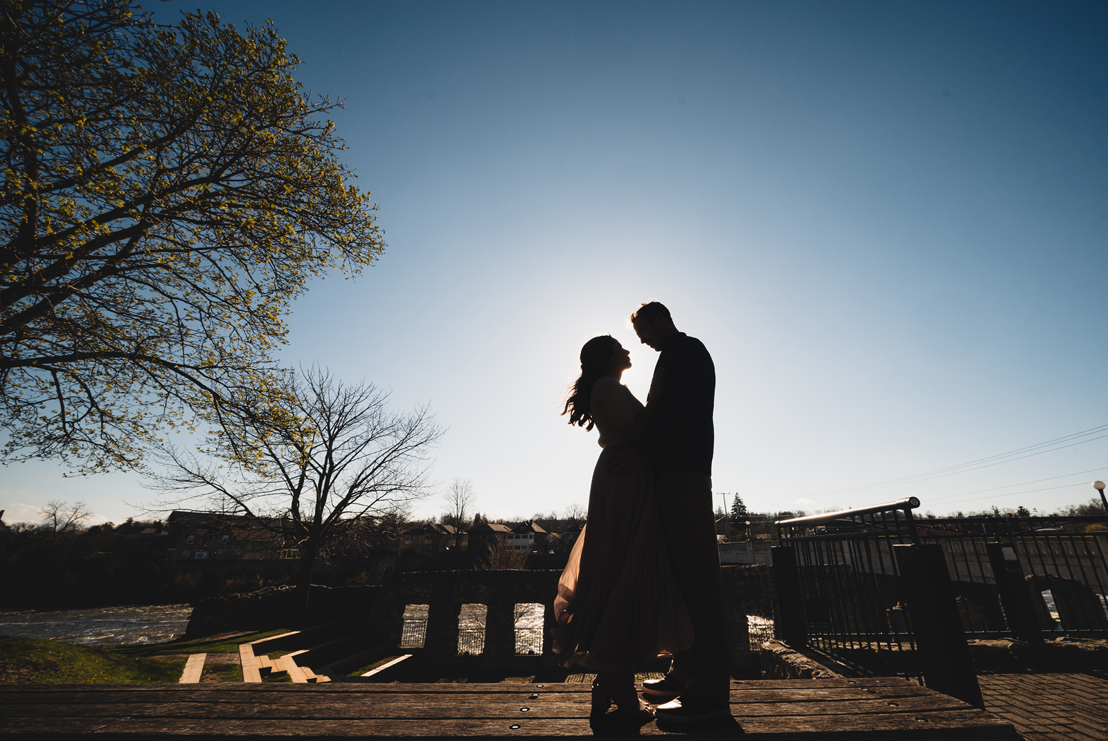 A couple on their engagement shoot, with an urban landscape in the background.